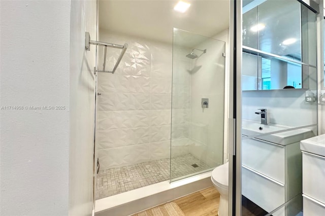 bathroom featuring tiled shower, hardwood / wood-style floors, and toilet