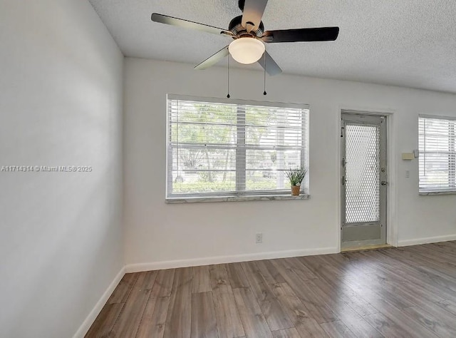 unfurnished room with hardwood / wood-style floors, a textured ceiling, a wealth of natural light, and ceiling fan