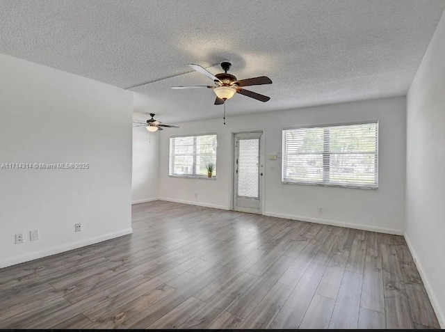 unfurnished room featuring a wealth of natural light, hardwood / wood-style floors, ceiling fan, and a textured ceiling