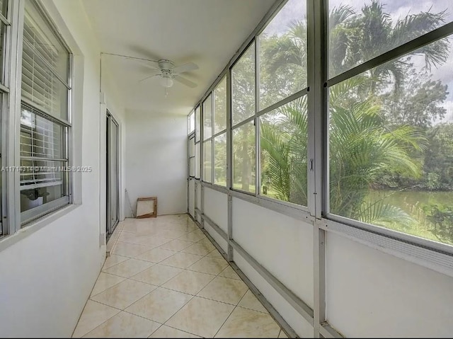 unfurnished sunroom with a water view and ceiling fan