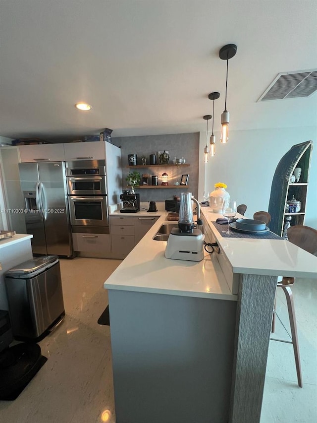 kitchen with kitchen peninsula, pendant lighting, a breakfast bar area, appliances with stainless steel finishes, and sink