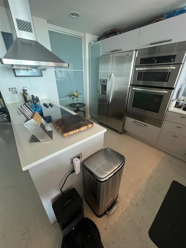 kitchen with white cabinets, stainless steel appliances, and wall chimney range hood