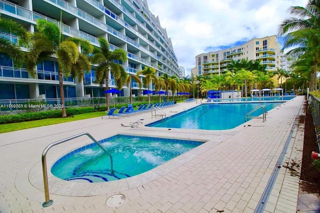 view of swimming pool featuring a hot tub and a patio