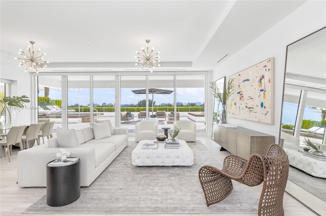 living room with light hardwood / wood-style floors, a wall of windows, and a chandelier