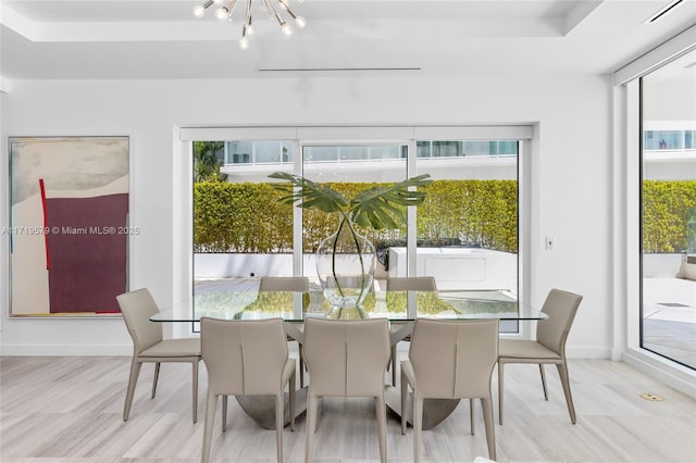 sunroom / solarium with a tray ceiling, plenty of natural light, and an inviting chandelier