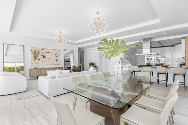 dining space with an inviting chandelier and a raised ceiling