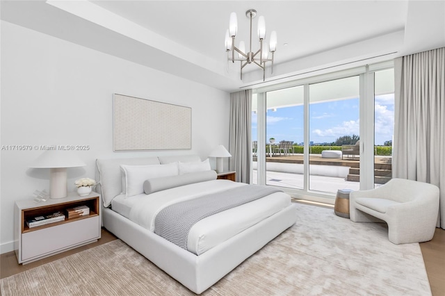 bedroom featuring access to exterior, an inviting chandelier, and hardwood / wood-style flooring