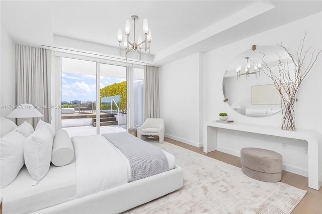 bedroom with access to outside, a raised ceiling, and hardwood / wood-style flooring