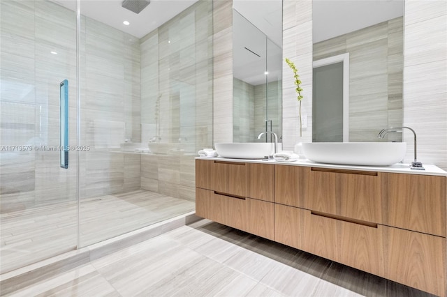 bathroom featuring tile patterned flooring, vanity, a shower with door, and tile walls