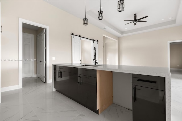 kitchen with a raised ceiling, a barn door, sink, and pendant lighting