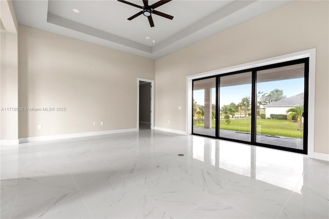 spare room featuring a raised ceiling and ceiling fan