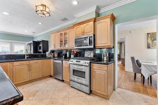 kitchen featuring dark stone countertops, stainless steel appliances, ornamental molding, and sink