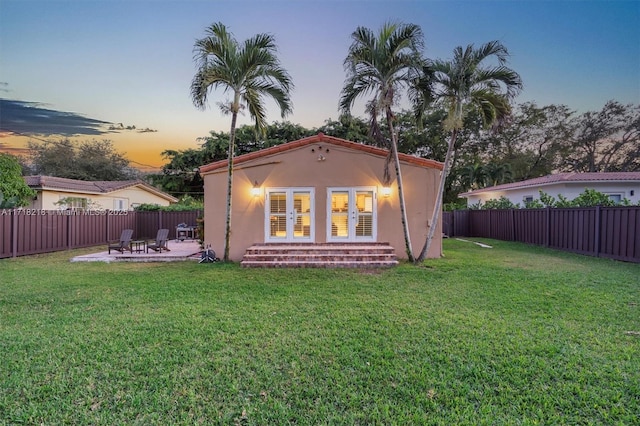 back house at dusk with a yard and a patio