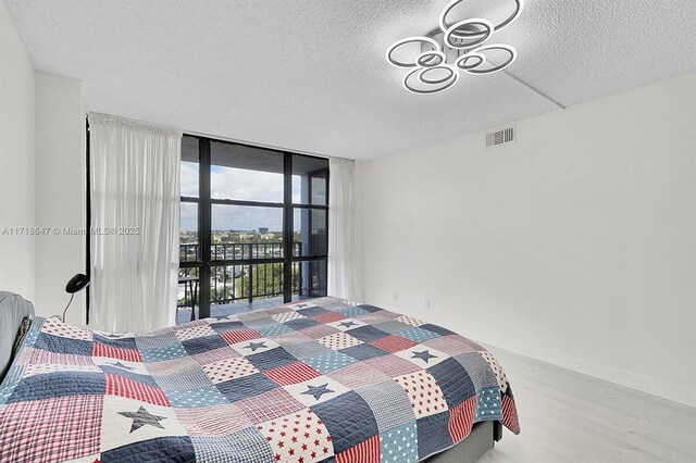 bedroom featuring light hardwood / wood-style floors, a textured ceiling, and a wall of windows