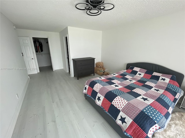 bedroom featuring a closet, light hardwood / wood-style floors, and a textured ceiling