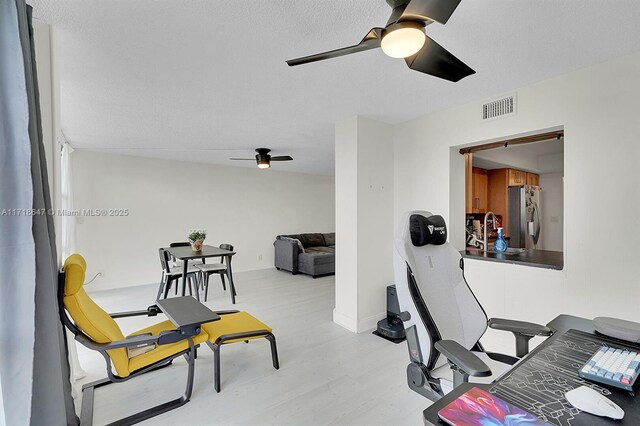 dining room with light hardwood / wood-style floors, a textured ceiling, expansive windows, and ceiling fan