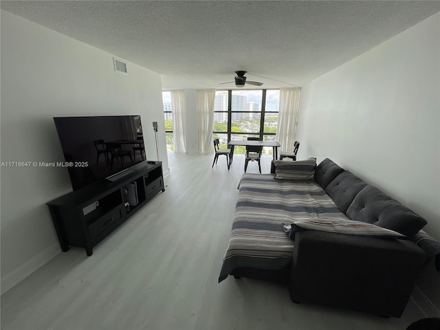 living room featuring light hardwood / wood-style floors, a textured ceiling, floor to ceiling windows, and ceiling fan