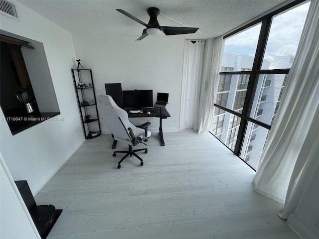 office area with a wall of windows, ceiling fan, and a textured ceiling