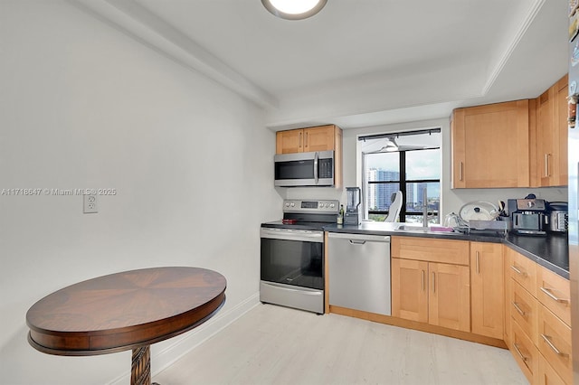 800 Parkview Dr Unit 1001, Hallandale Beach, FL 33009 - kitchen featuring appliances with stainless steel finishes, light brown cabinets, dark countertops, light wood-style floors, and baseboards