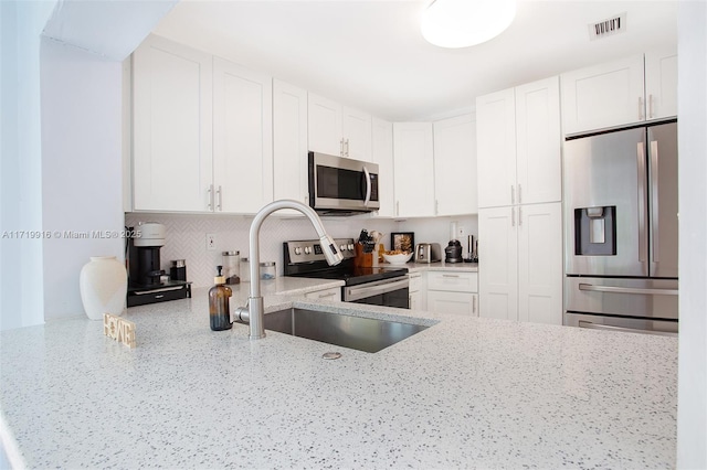 kitchen featuring sink, stainless steel appliances, light stone countertops, and white cabinetry