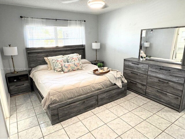 tiled bedroom featuring ceiling fan and a textured ceiling