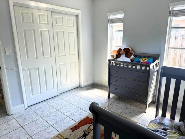 bedroom featuring ceiling fan, light tile patterned floors, a closet, and multiple windows