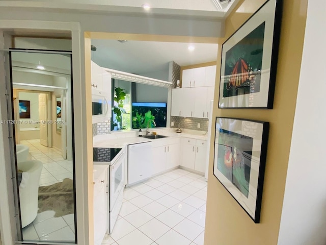 kitchen with light tile patterned floors, decorative backsplash, white appliances, white cabinets, and sink