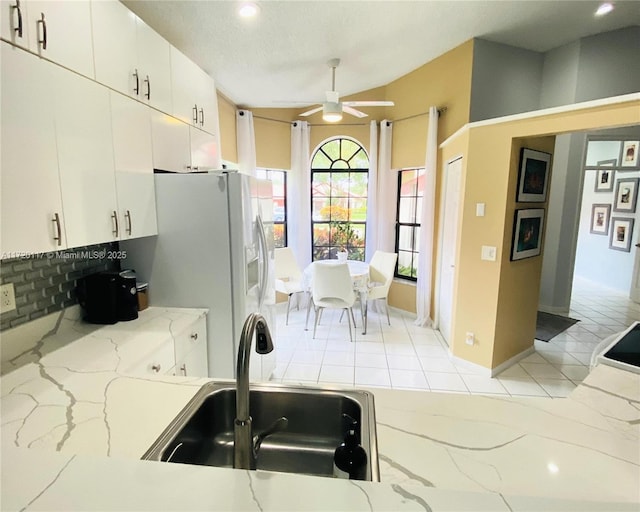 kitchen featuring white fridge with ice dispenser, white cabinetry, tasteful backsplash, sink, and ceiling fan