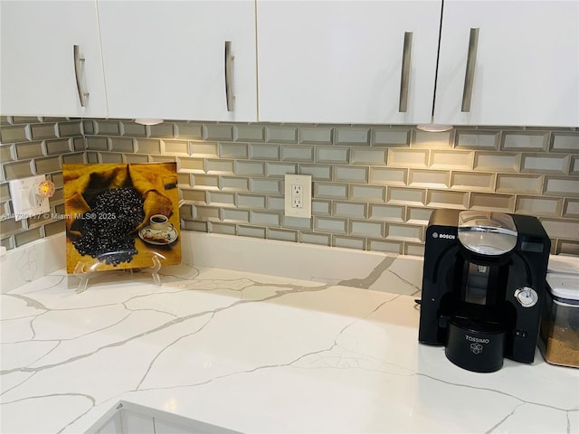 room details with decorative backsplash, white cabinets, and light stone countertops