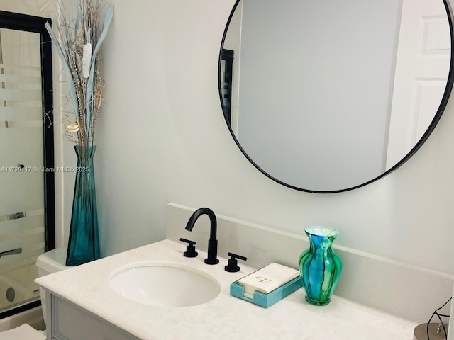 bathroom featuring a shower with shower door, vanity, and toilet