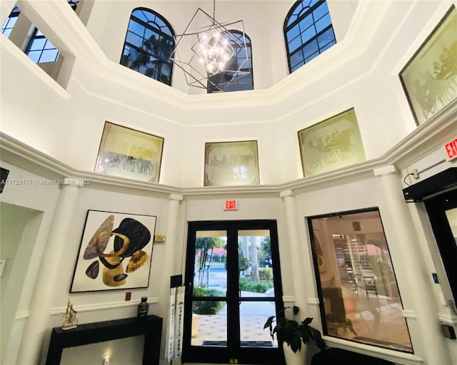 interior space with a high ceiling, a notable chandelier, and french doors