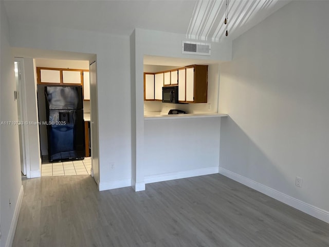 interior space featuring black appliances and hardwood / wood-style flooring