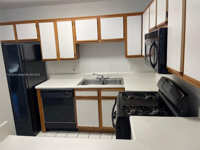 kitchen with light tile patterned floors, sink, white cabinetry, and black appliances