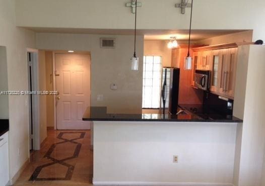 kitchen with black fridge, kitchen peninsula, and hanging light fixtures