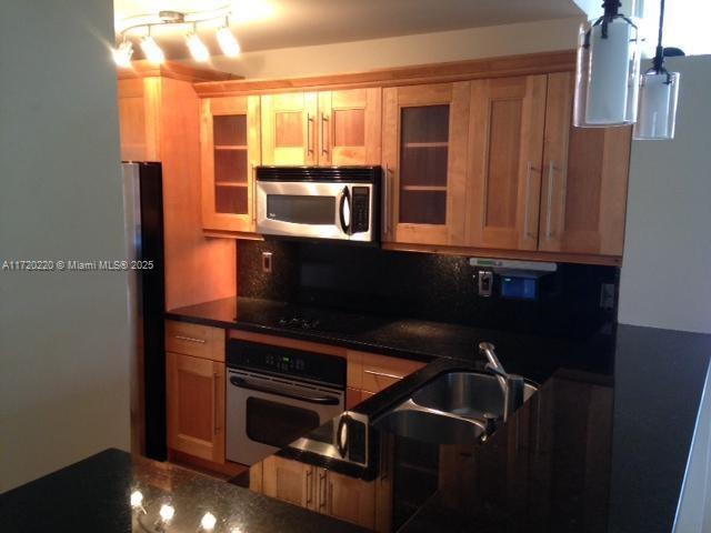 kitchen featuring tasteful backsplash, sink, dark stone counters, and appliances with stainless steel finishes