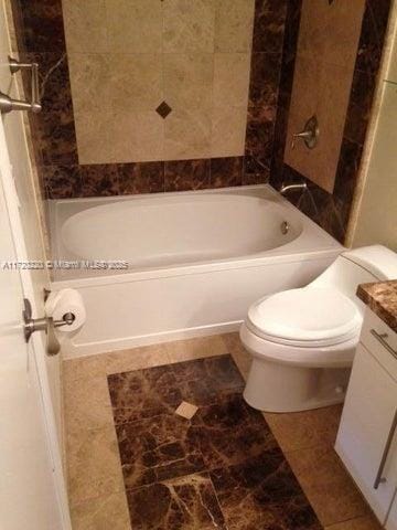 full bathroom with tiled shower / bath, vanity, and toilet