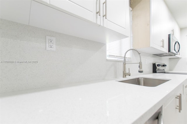 kitchen with sink, white cabinets, and range