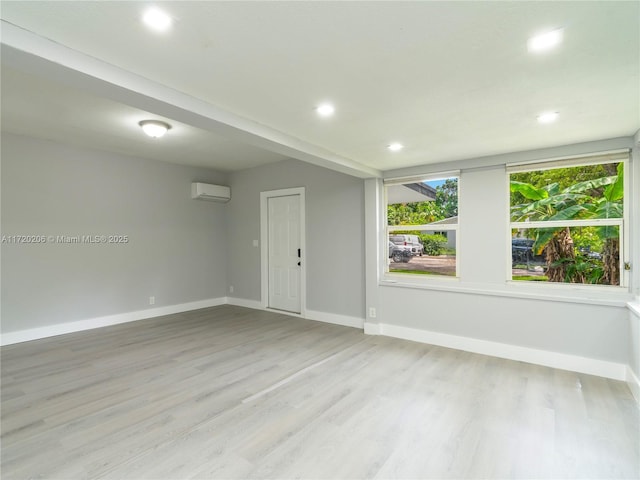 spare room with a wall mounted AC and light wood-type flooring