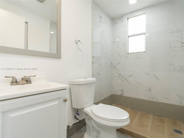 bathroom with tiled shower, vanity, and toilet