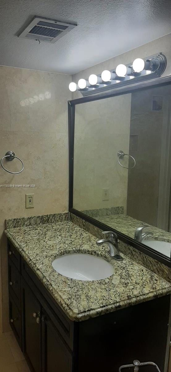 bathroom featuring tile patterned flooring, vanity, and a textured ceiling