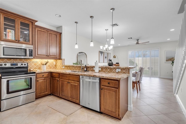 kitchen featuring hanging light fixtures, ceiling fan, light stone countertops, kitchen peninsula, and stainless steel appliances