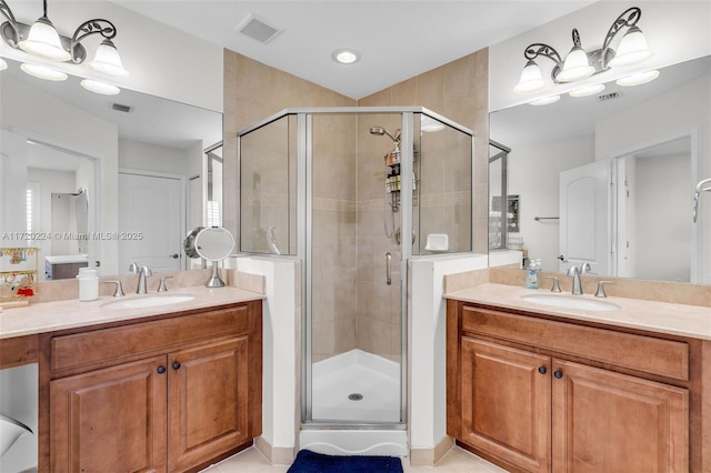 bathroom featuring vanity, an inviting chandelier, tile patterned floors, and a shower with door