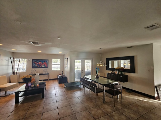 dining area with a notable chandelier, french doors, and dark tile patterned flooring