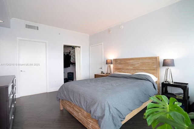 bedroom with dark wood-type flooring, a closet, and ornamental molding