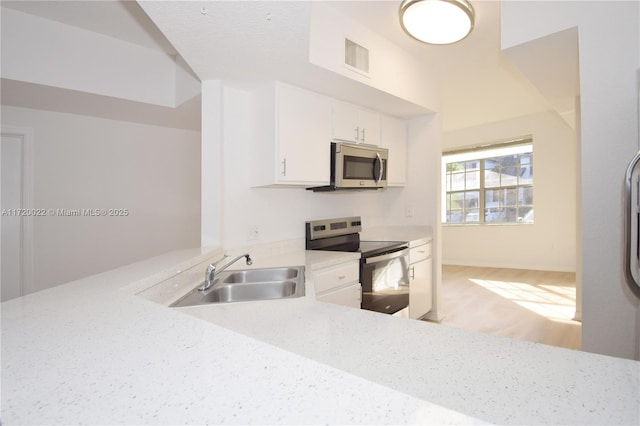 kitchen featuring sink, white cabinetry, light stone counters, and appliances with stainless steel finishes