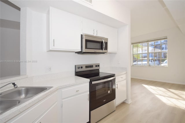 kitchen featuring white cabinets, light wood-type flooring, appliances with stainless steel finishes, and sink