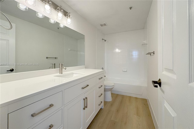 full bathroom featuring hardwood / wood-style flooring, toilet, tiled shower / bath, and vanity