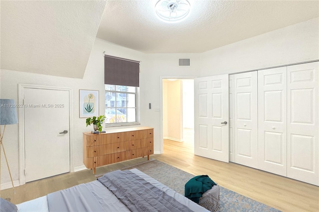 bedroom featuring a closet, light hardwood / wood-style flooring, and a textured ceiling