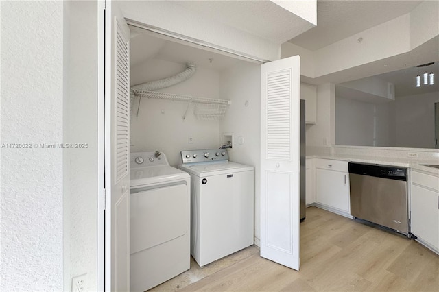 laundry room with washing machine and clothes dryer and light wood-type flooring