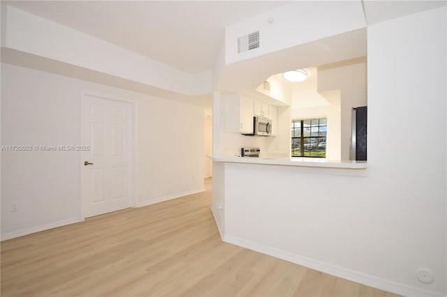 kitchen with white cabinetry, appliances with stainless steel finishes, kitchen peninsula, and light wood-type flooring